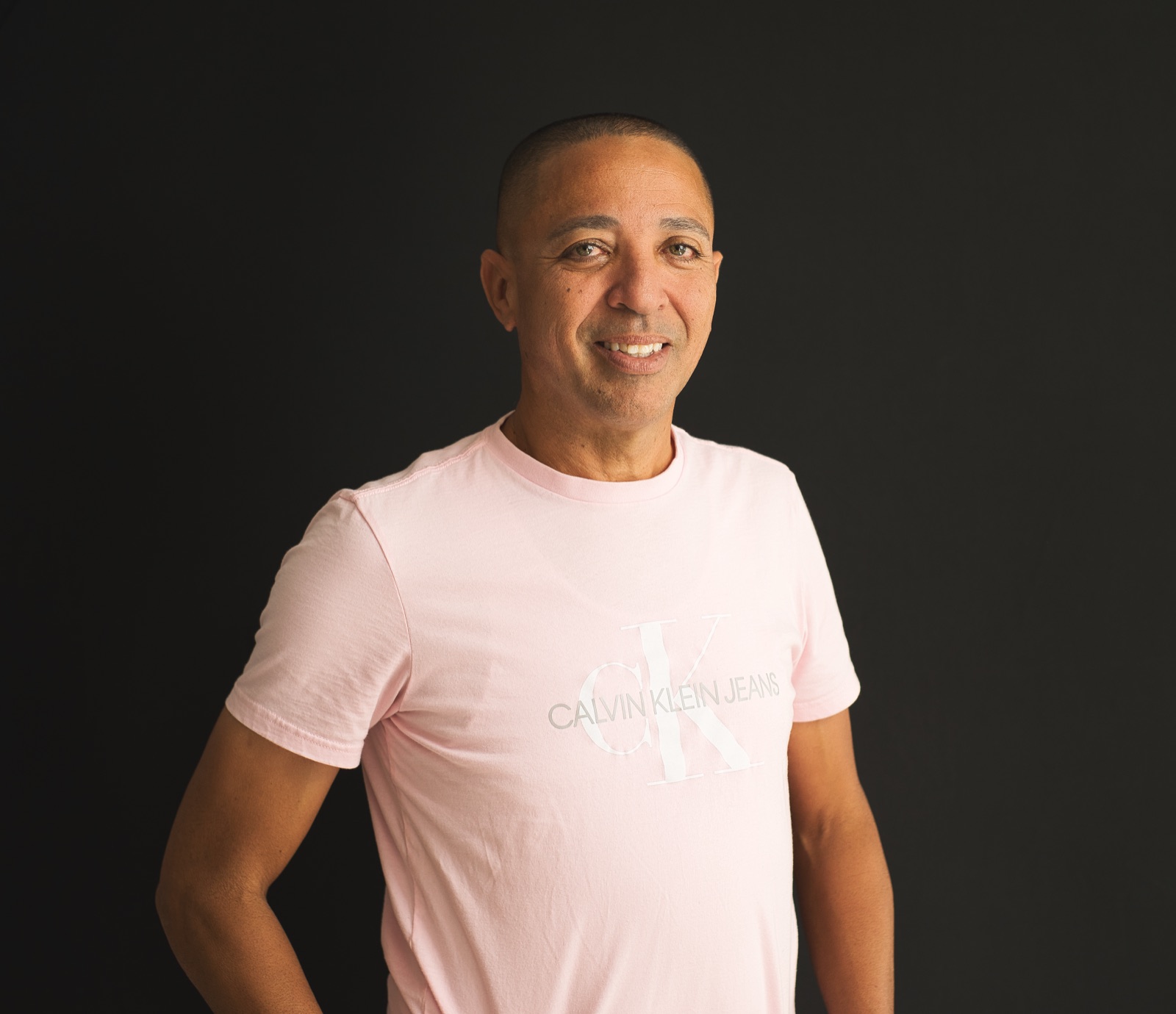 Retrato masculino sonriente con fondo oscuro y camiseta clara
