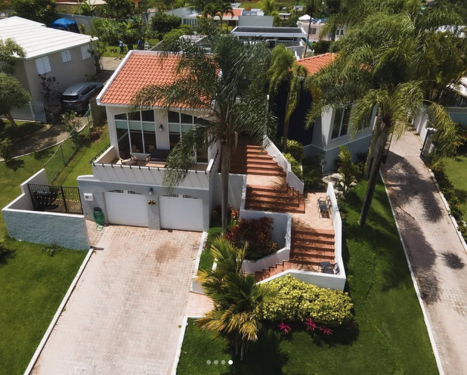 Villa con techo de teja entre palmeras y escaleras decorativas