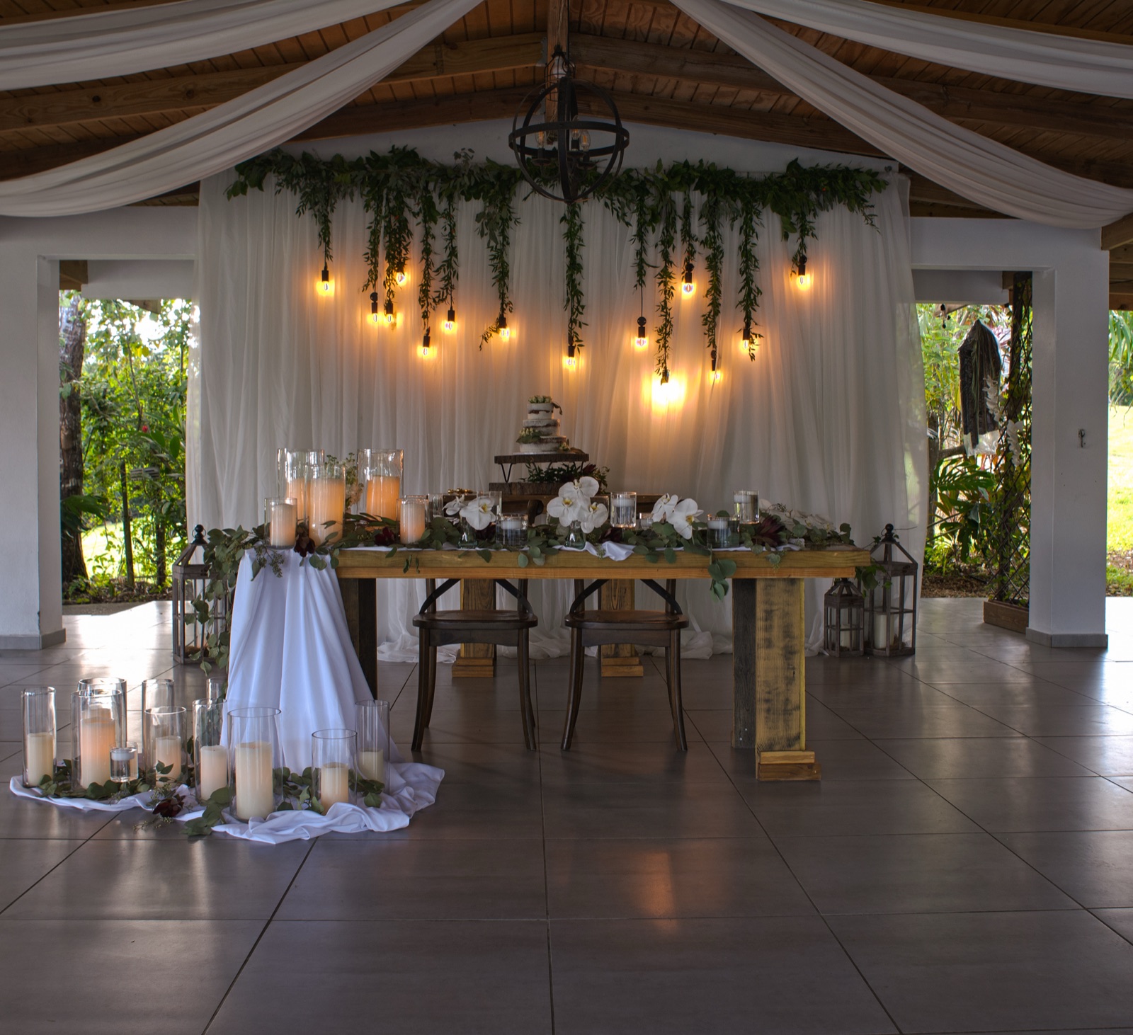 Interior de salón de bodas con cortinas, velas y luces colgantes